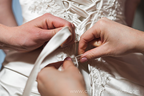 bridesmaids tying bow on back of bride's dress