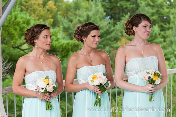 three bridesmaids wearing seafoam dresses with bouquets